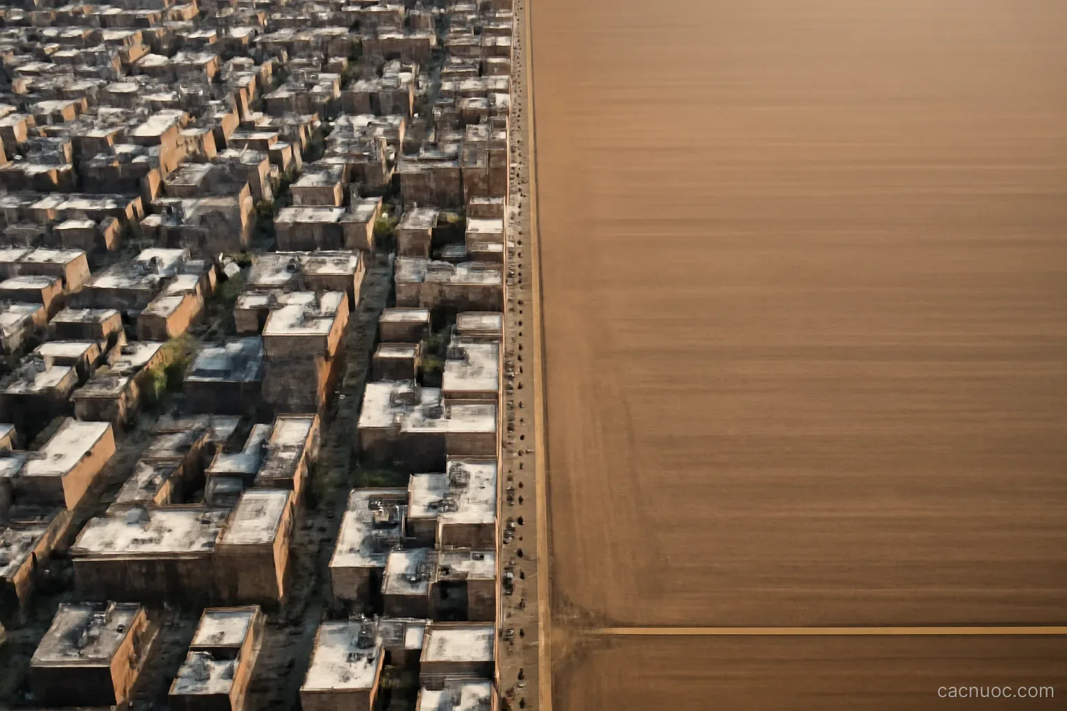 Aerial contrast of a dense city block next to wide empty farmland, no readable text